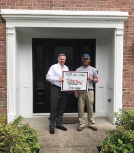 Satisfied Energy Swing Windows customer posing for photo in front of newly installed replacement door with sidelites.