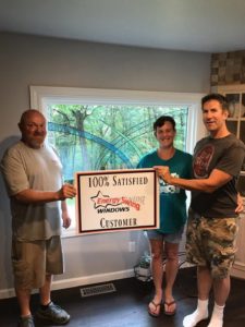 Energy Swing Windows employee standing alongside two satisfied customers in front of newly installed window.