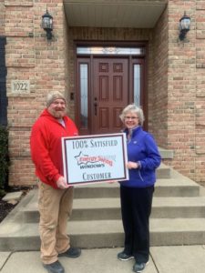 Energy Swing Windows employee wearing read jacket is standing alongside a satisfied customer in front of newly installed front door.
