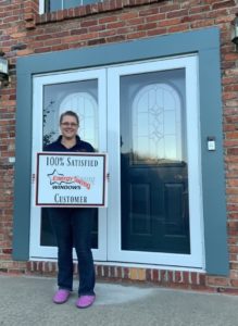 Satisfied customer posing for photo in front of newly installed entry doors and storm doors.