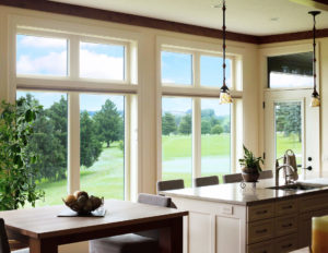 Interior of home with kitchen island, modest dining table, and seven large picture windows.