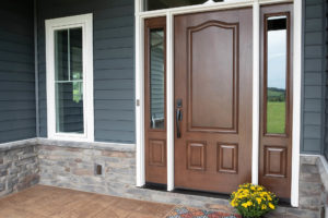 Front porch of single-family home with gray siding, white trim, and brown steel entry door with a sidelite on either side.