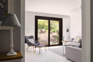 Modern living area with minimalistic walls, wood flooring, and black-frame sliding patio doors leading to patio.