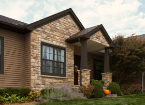 Exterior of home with brick exterior walls, a manicured lawn, and dark brown wood-frame windows.